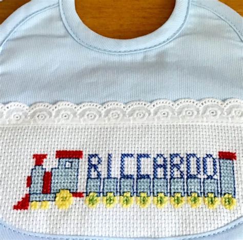 Un dettaglio ravvicinato di un ricamo a punto croce su un bavaglino per neonati con fili colorati