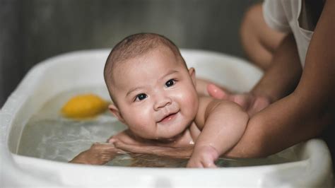 Newborn boy being bathed by parent
