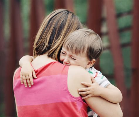 Bambino che piange mentre il papà cerca di abbracciarlo e la mamma lo tiene