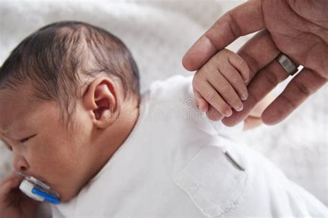 Neonato che stringe il dito del genitore