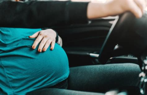 Donna incinta serena in auto con il partner che guida