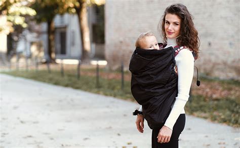 Coppia con bambino in marsupio indossando una giacca portabebè
