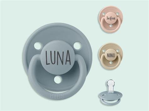 Un ciuccio personalizzato con il nome di un bambino inciso sul corpo in plastica colorata