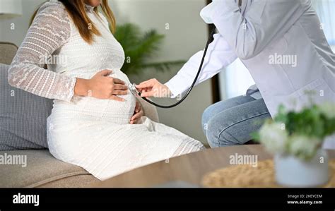 Coppia di futuri genitori che ascoltano il battito cardiaco del bambino con il doppler, sorridendo