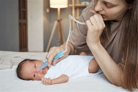 Parent using nasal aspirator on baby after saline application