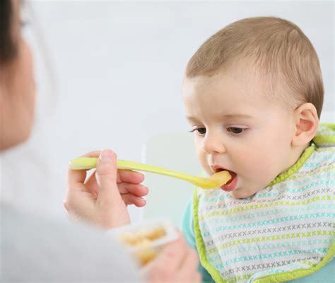 Bambino di 8 mesi che gioca con un cucchiaino, in un contesto che suggerisce l'introduzione di cibi solidi