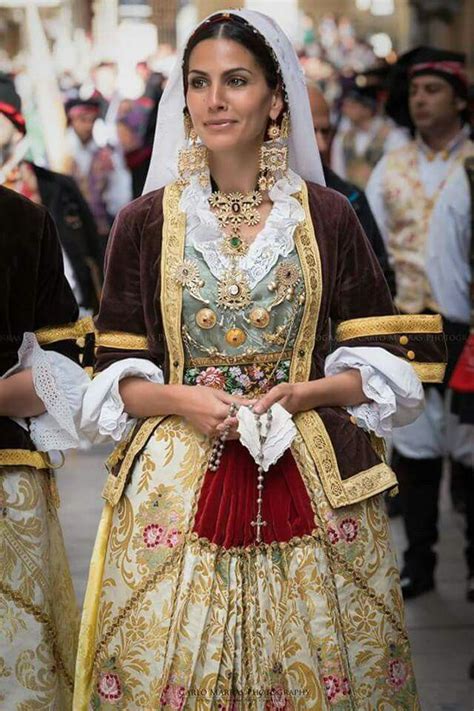 Una donna sarda in costume tradizionale che canta vicino a una culla
