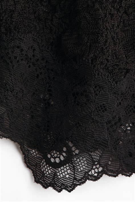 Donna che indossa un bodystocking di pizzo nero con dettagli trasparenti