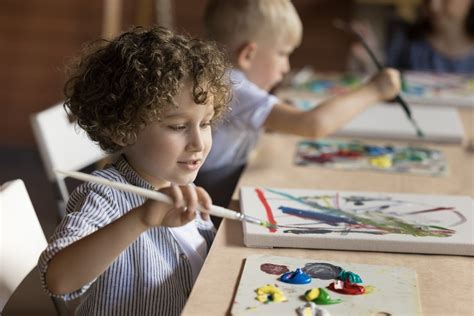 Bambini che colorano con tempere e foglie