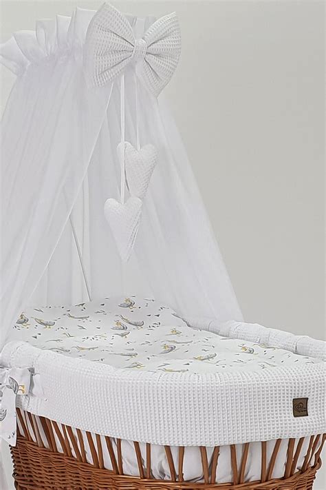 Un elegante set di biancheria per culla in tonalità neutre con una copertina in piquet finemente lavorata