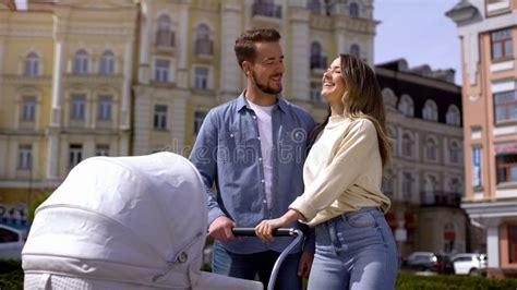 Genitori che passeggiano con un trio passeggino in un parco