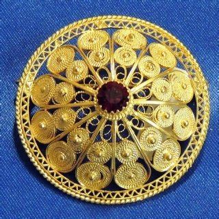 fotografia ravvicinata di un gioiello in filigrana sarda che riprende motivi arcaici della Dea Madre