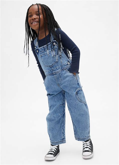 Bambina in salopette jeans con t-shirt a righe