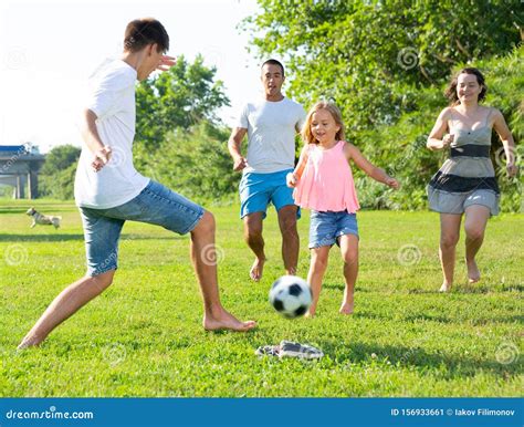 Bambini che giocano a calcio sulla spiaggia con i genitori