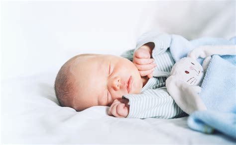 neonato che dorme serenamente in culla indossando abiti in cotone naturale