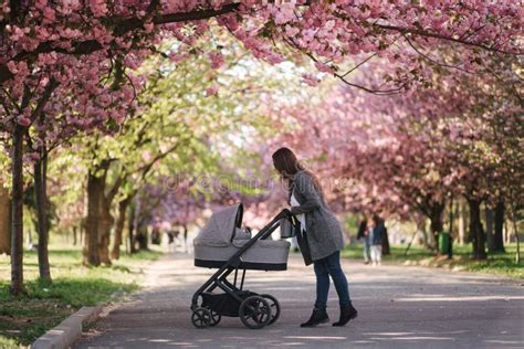 Mamma che cammina in un parco portando il bambino in fascia