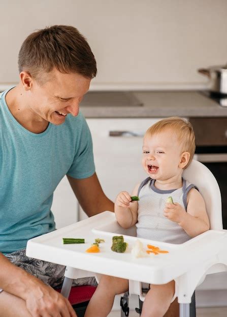 padre che aiuta il bambino a mangiare nel seggiolone