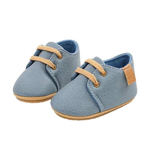 Scarpe per neonato eleganti in pelle scamosciata adagiate su una superficie morbida