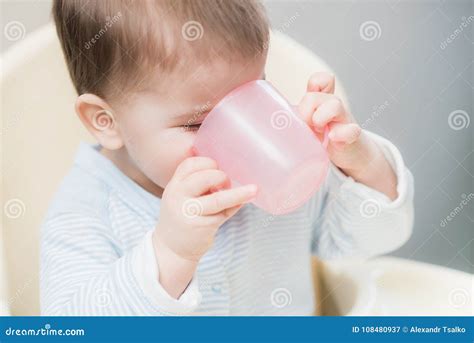 Bambino che beve da una tazza aperta con manici