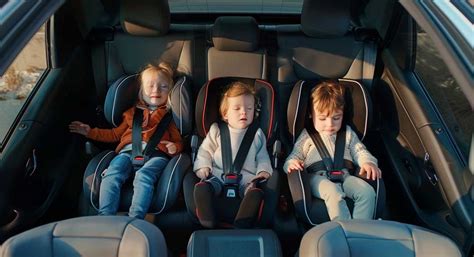 Famiglia felice in auto con tre seggiolini per bambini