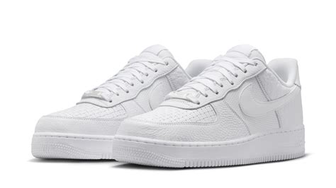 Un paio di Nike Air Force 1 bianche posizionate accanto a dei piccoli giocattoli per bambini