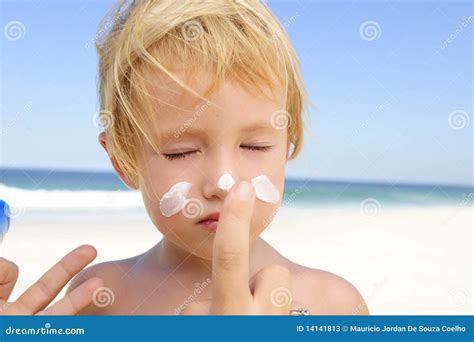 Bambino che gioca in spiaggia con la crema solare