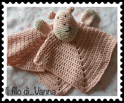 Un pupazzetto doudou in lana colorata poggiato accanto a una manina di neonato, simbolo dell'affetto e del legame familiare.