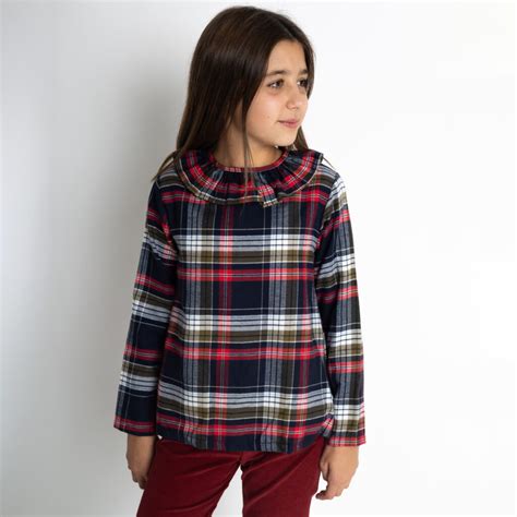 Bambina con camicia scozzese in un parco