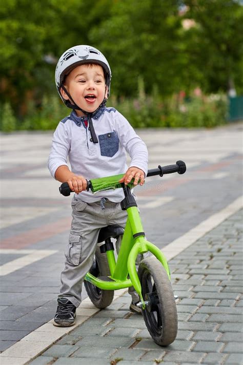 Bambino con casco e bici senza pedali in un parco