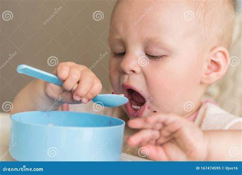 neonato che impara a mangiare da solo usando le mani e il cucchiaino