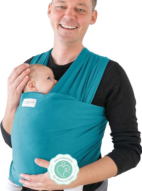 genitore che porta il proprio bambino in fascia in un parco