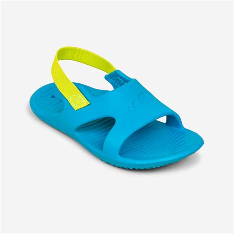Bambino che indossa sandali colorati in gomma in riva al mare
