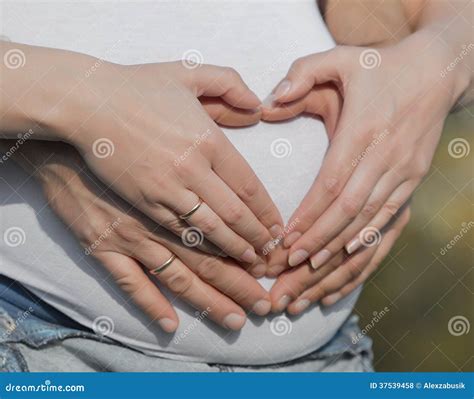 Donna incinta con le mani sul pancione e un cuore disegnato