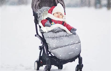 Bambino sorridente avvolto in un sacco termico su un passeggino in un paesaggio invernale
