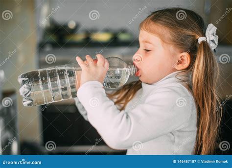 neonata che beve da un bicchierino con l'aiuto di un adulto