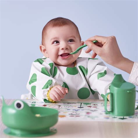 bambino che gioca e mangia indossando un bavaglino a maniche lunghe Lässig