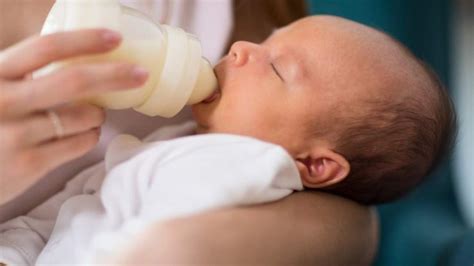 Neonato che beve dal biberon in posizione corretta
