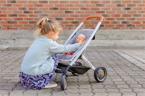 Bambina che gioca con un passeggino per bambole Maxi Cosi