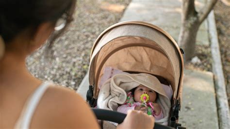 Dettaglio di Barbie mentre spinge un passeggino moderno in un contesto urbano fashion