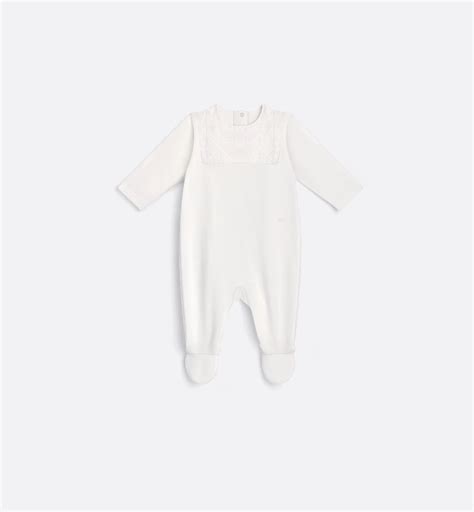 Un set regalo per neonati Hermès finemente disposto su un piano di legno chiaro, che evidenzia la texture del cotone biologico e i ricami artigianali.