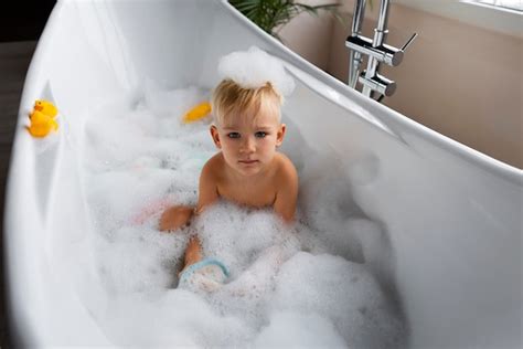 Un bambino felice che gioca in una vasca da bagno colorata con accessori a tema unicorno
