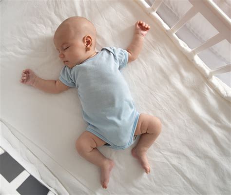 Neonato che dorme supino in una culla con riduttore