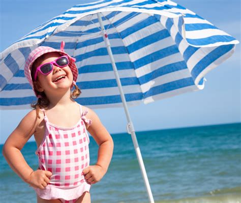Bambino in spiaggia al riparo dell'ombrellone con indumenti leggeri