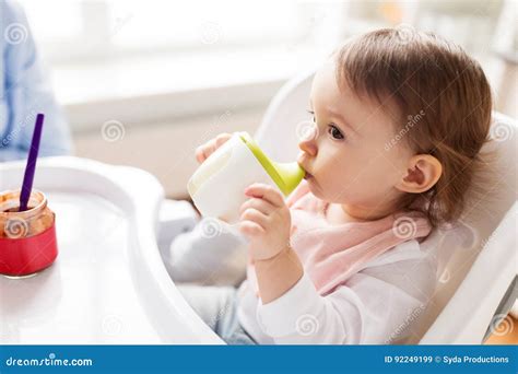 bambino felice che beve dalla tazza antigoccia