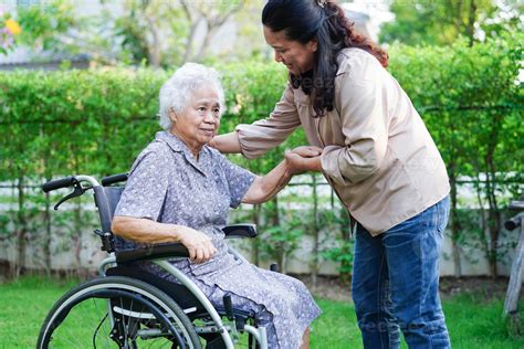 Persona anziana sorridente con un caregiver, entrambi in un ambiente domestico accogliente, con un pacco di pannolini Tena in evidenza sul tavolo.