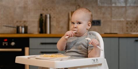 Genitori che imboccano il bambino nel seggiolone durante il pasto