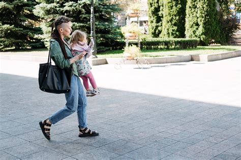 Mamma che cammina in un parco naturale con il suo bambino in un marsupio ergonomico