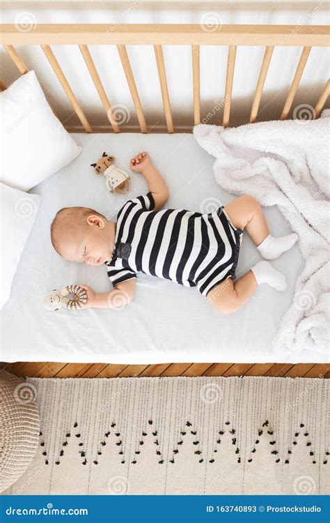 Bambino che dorme sulla schiena in una culla, con un ambiente di sonno sicuro e privo di oggetti superflui