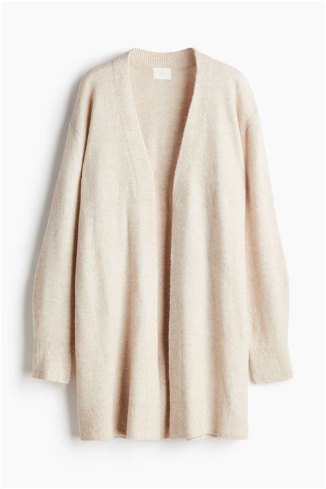 Donna che indossa un cardigan lungo beige sopra una tuta casual in un ambiente luminoso