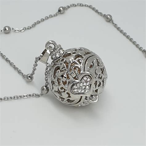 un chiama angeli appeso a una collana con sfondo sfocato di una pancia di donna incinta